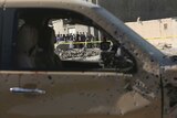 Car with bullet holes, and people can be seen through the window