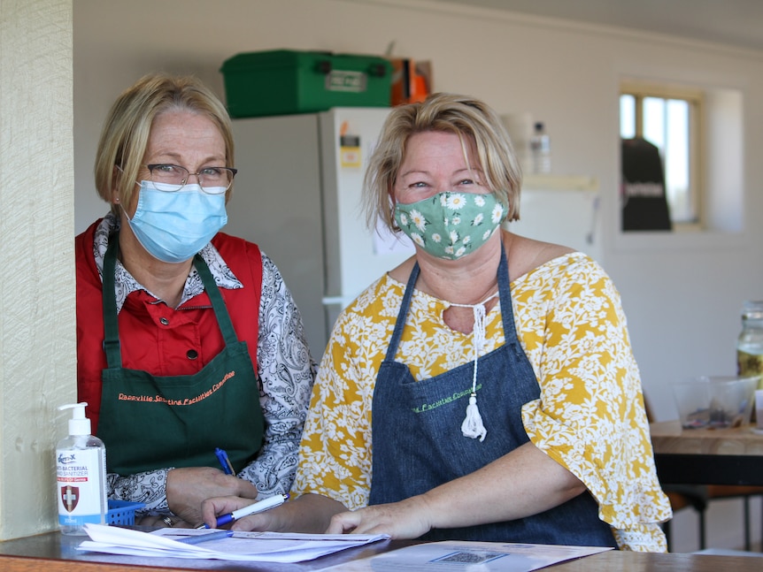 Two female members of the organising committee wearing masks in the canteen.