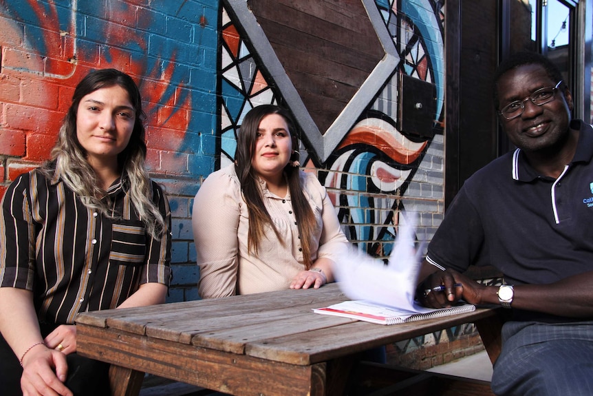 A client, interpreter and case worker sit together at a table.