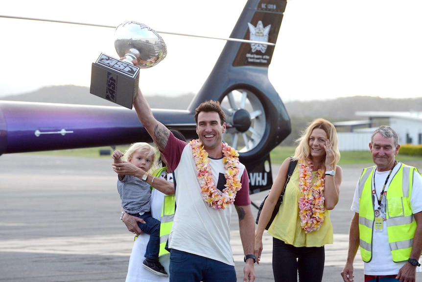 Coming home triumphant ... Joel Parkinson shows off his world surfing title gong.