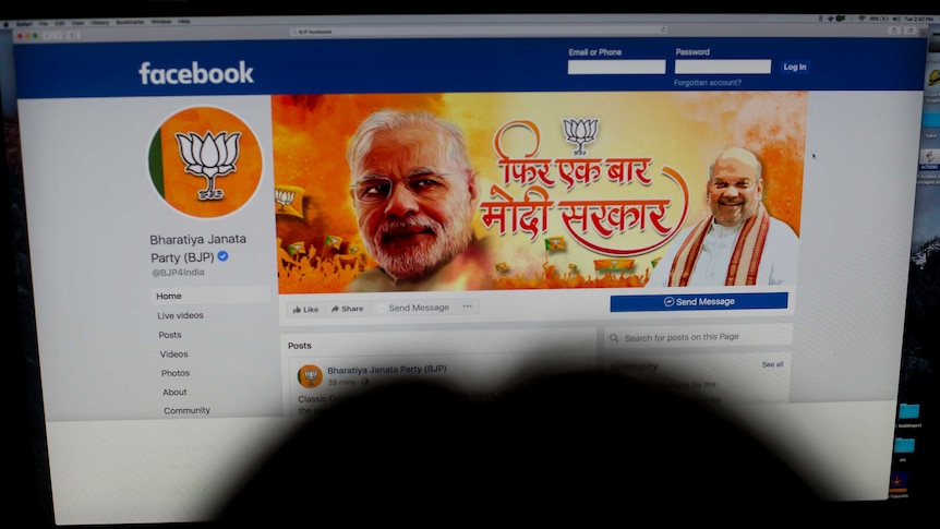 A person opens an official facebook page of the BJP party with a photo of Narendra Modi on the banner