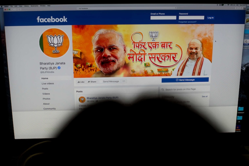 A person opens an official facebook page of the BJP party with a photo of Narendra Modi on the banner