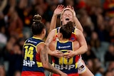 Jess Waterhouse jumps into the arms of one of her teammates and smiles