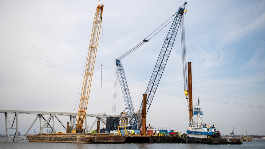 Barge cranes are shown near the collapsed Francis Scott Key Bridge on the Patapsco River.