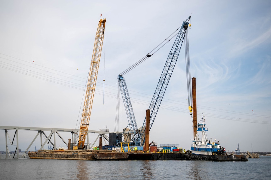 Barge cranes are shown near the collapsed Francis Scott Key Bridge on the Patapsco River.