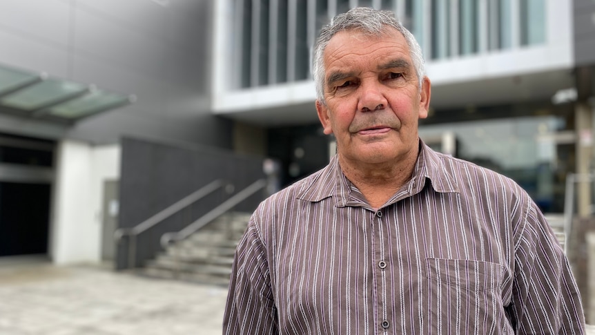 an elderly man standing outside court