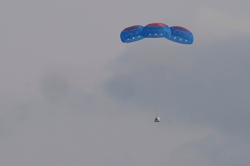 A rocket glides to earth under three giant parachutes