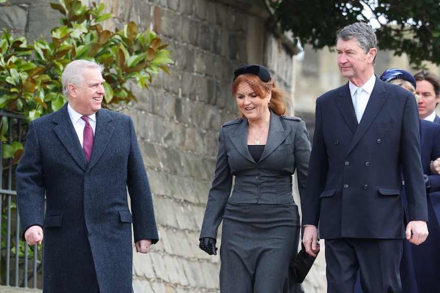 Prince Andrew wearing a suit walks beside the Duchess of york and Vice Admiral near a church.