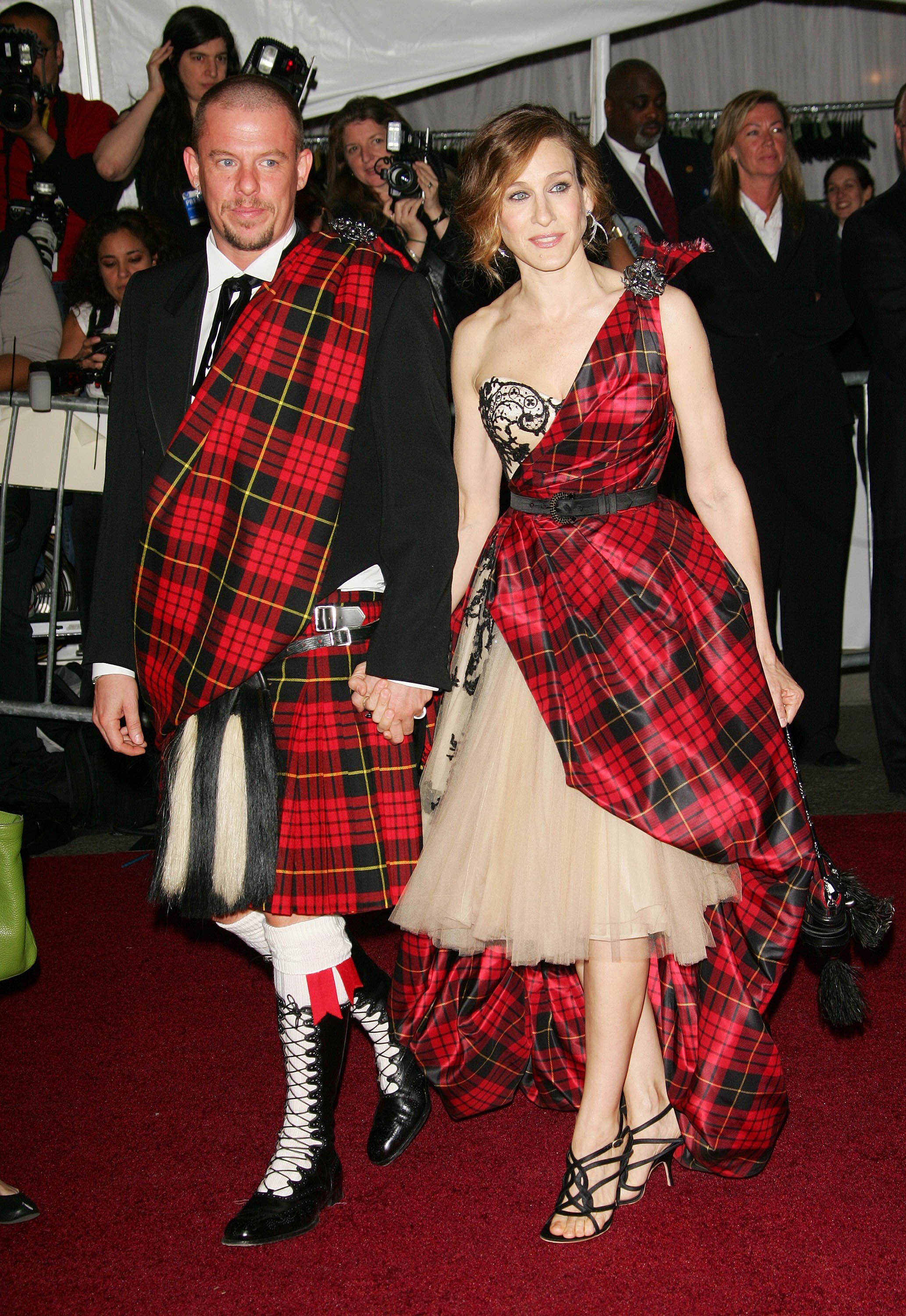 30-something white man with close-shaved head wearing suit and tartan sash with 30-something white woman in tartan dress.