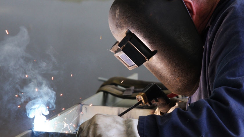 A man in a protective mask using an arc welder