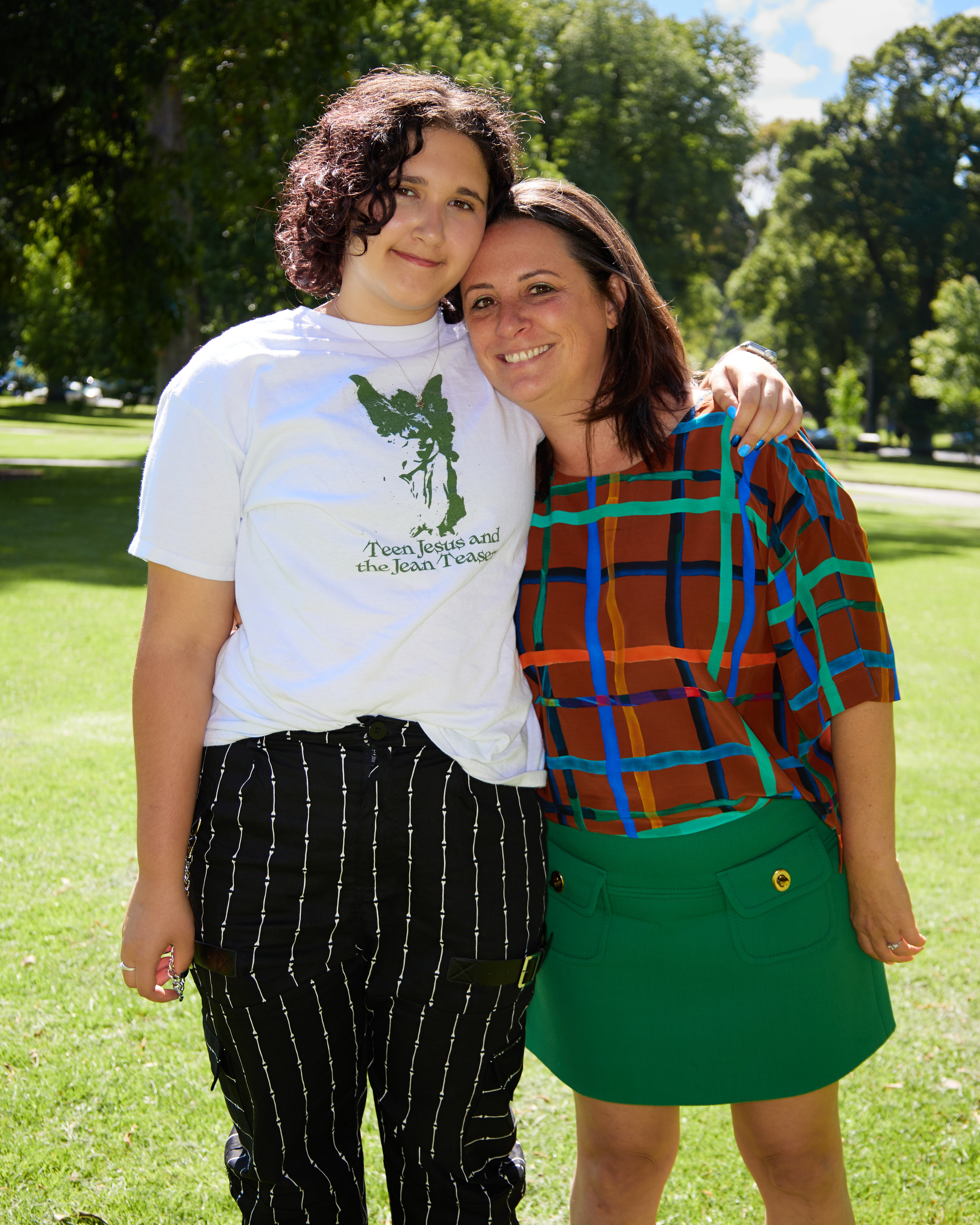 Simone Kelly and stepson Eli stand outside and hug while facing the camera.