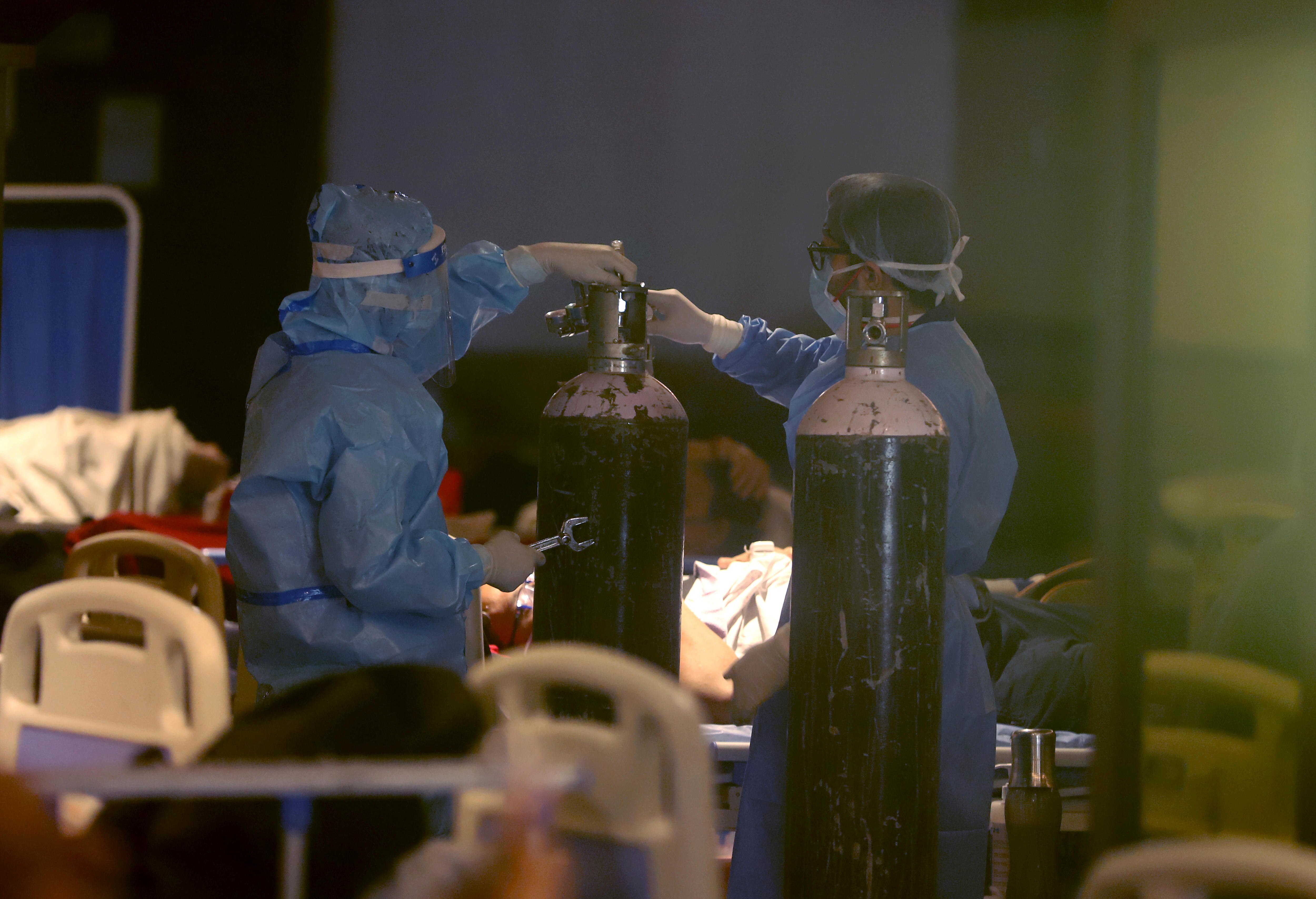 Medical workers using personal protective equipment install oxygen tanks