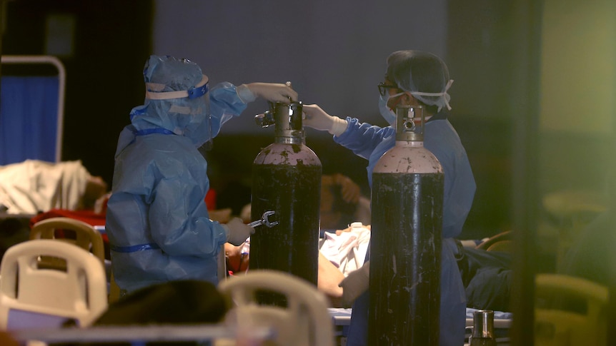 Medical workers using personal protective equipment install oxygen tanks