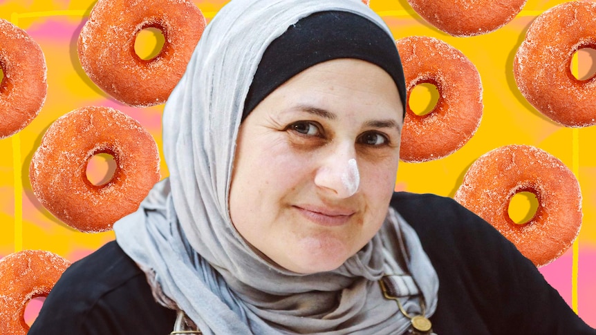 Frida Deguise smiling to the camera. Behind her are frosted donuts against a yellow and pink background.