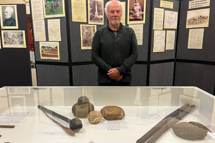 A man stands near displays of indigenous artifacts and information.