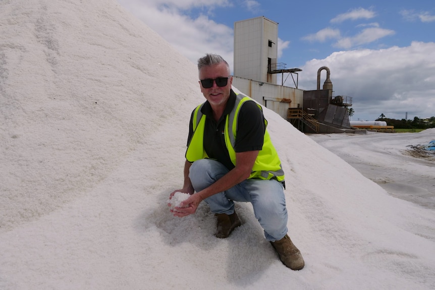 Michael McNamara kneels in a salt pile at Australian Saltworks' Bowen operation