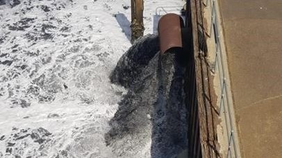 black water entering port river from a concrete pipe