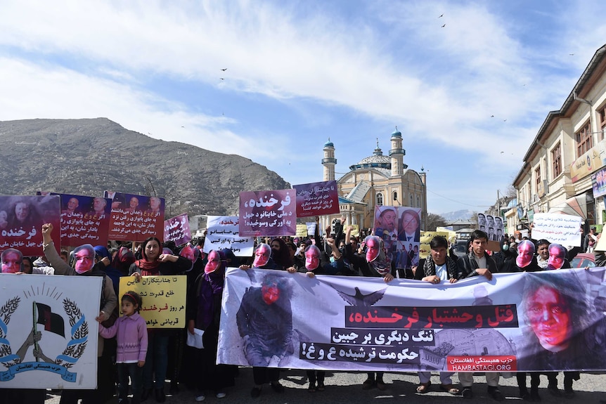 Hundreds walk the streets of Kabul wearing masks and holding signs