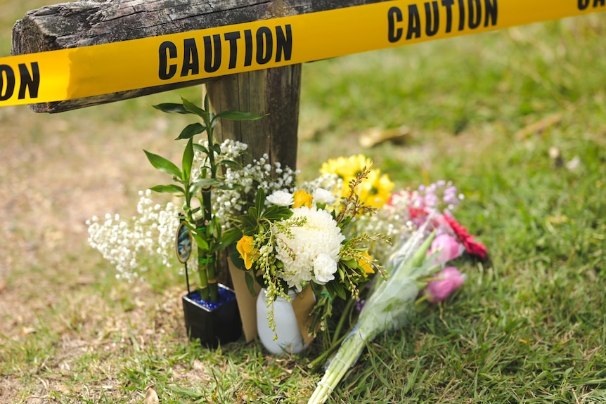 Flowers near a fence post marked by 'caution' tape