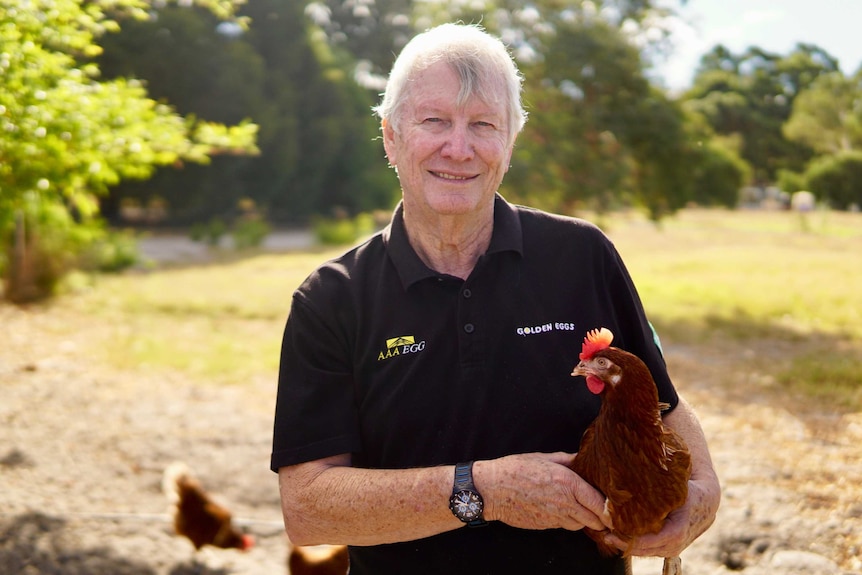 A middle-aged man holds a chicken