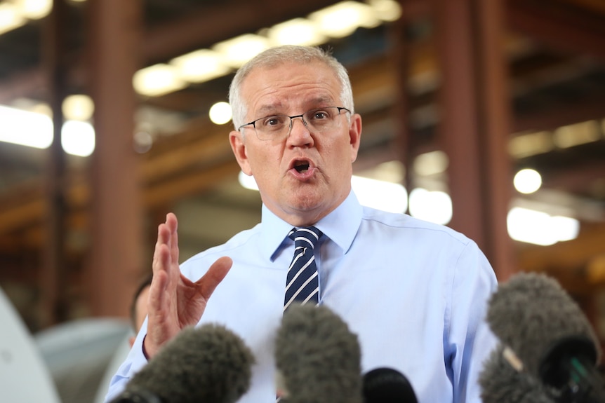 Morrison speaks and gestures during a press conference. 