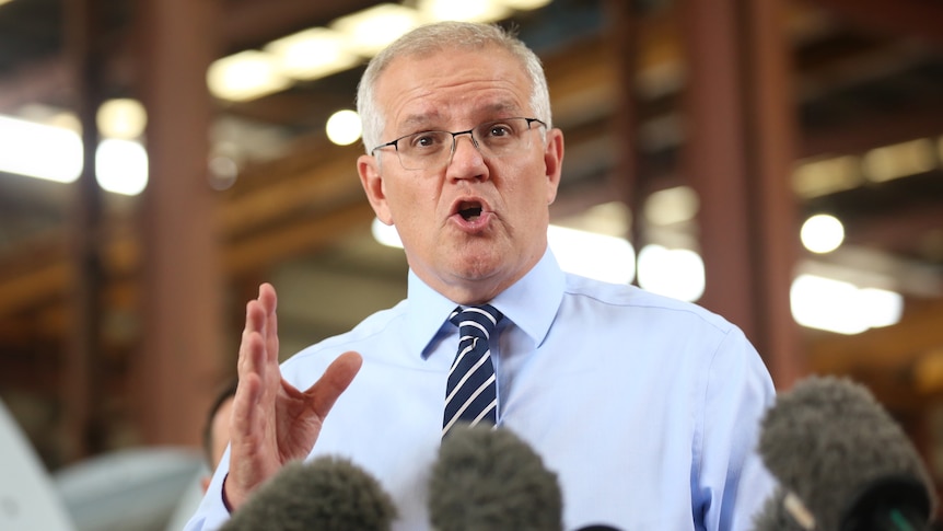 Morrison speaks and gestures during a press conference. 