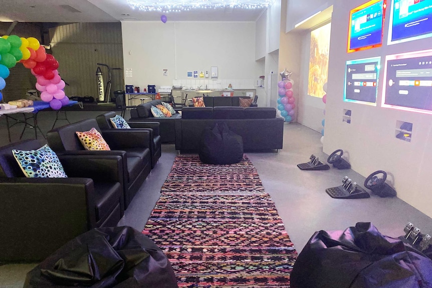 Empty couches inside a youth drop-in centre in Alice Springs, with projections of computer games on the wall.