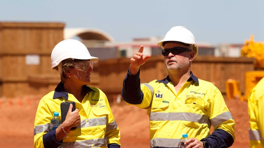 Mine bosses during a site visit wearing hard hats.