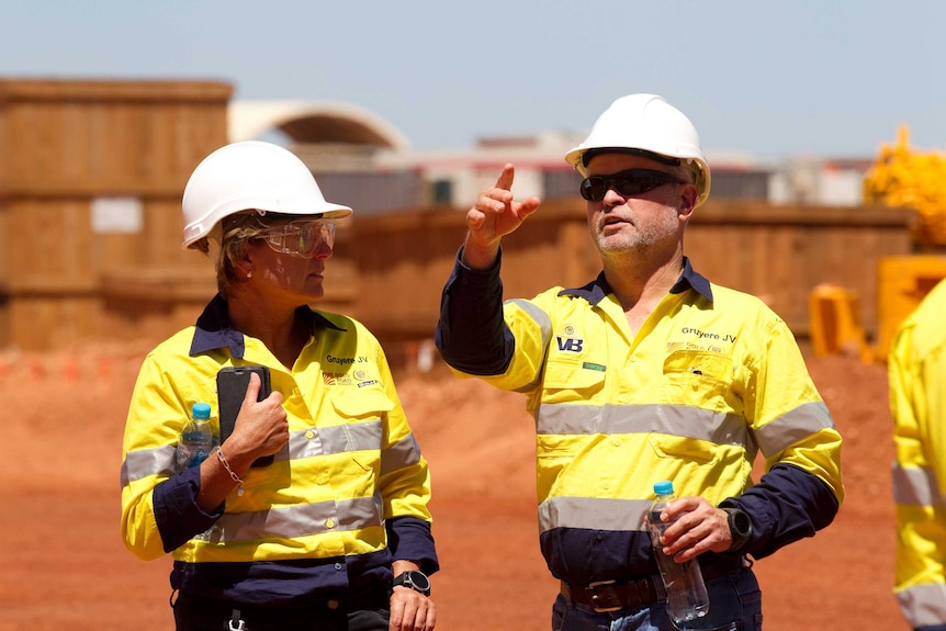 Mine bosses during a site visit wearing hard hats.