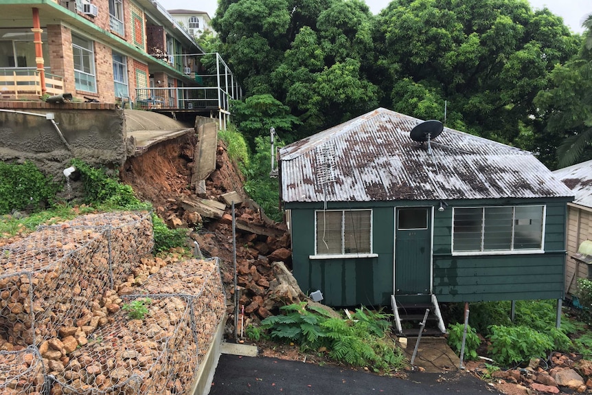 Retaining wall collapses at Townsville unit block into house next door.