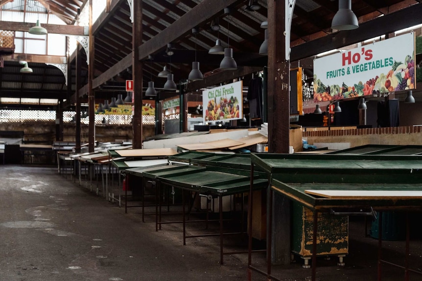 Empty fruit and vegetable market stall tables in covered market
