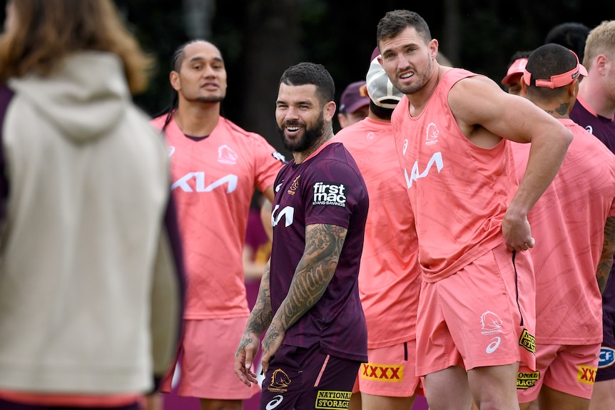 adam reynolds and corey oates stand among a group of broncos players during a public training session