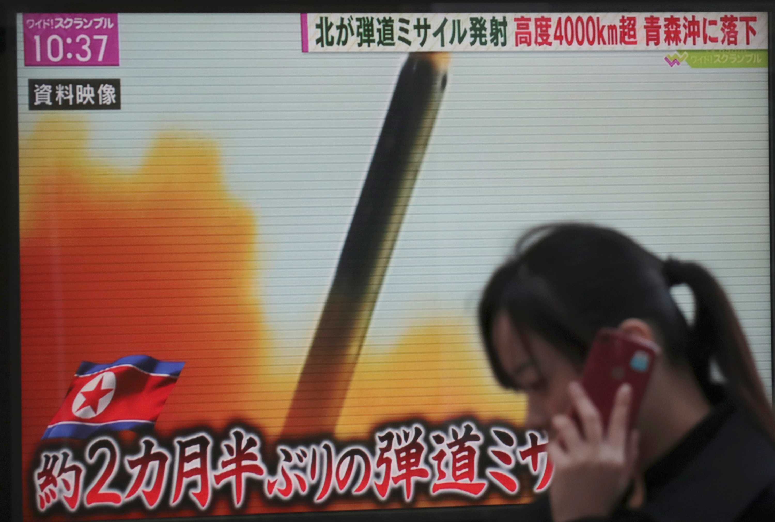 A woman walks past a TV screen broadcasting news of North Korea's missile launch