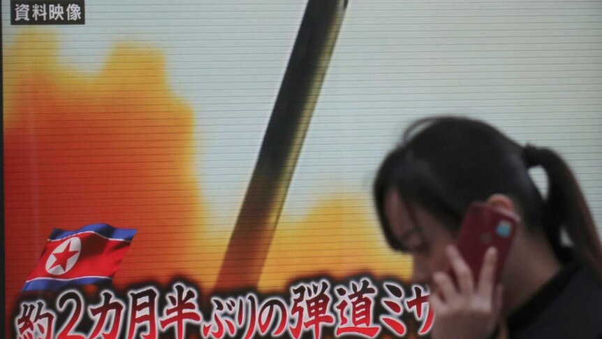 A woman walks past a TV screen broadcasting news of North Korea's missile launch