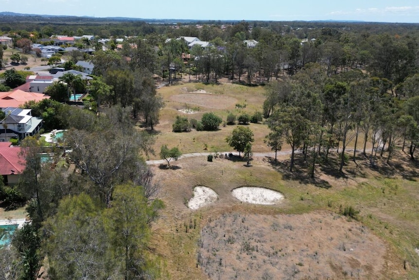 An aerial image showing the boundary of suburban homes and a disused golf course.