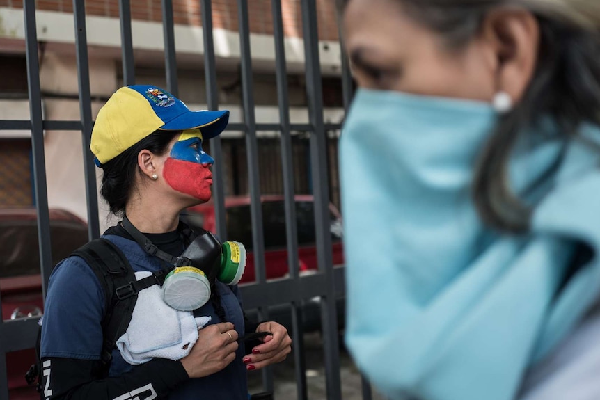A woman wears red blue and yellow face paint.