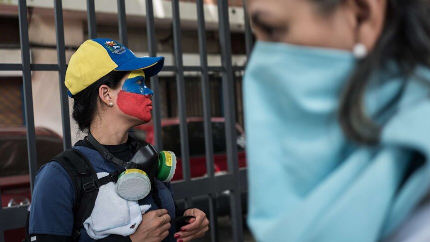 A woman wears red blue and yellow face paint.