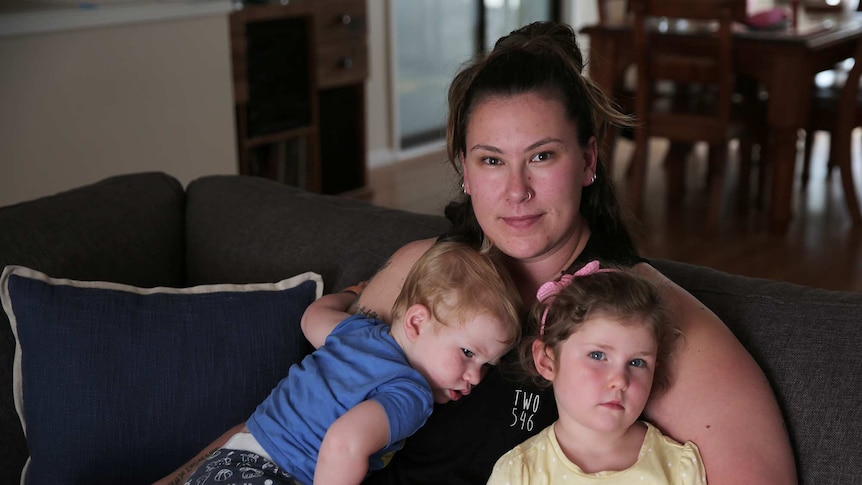 A woman sits with her children on a couch