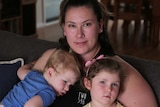 A woman sits with her children on a couch