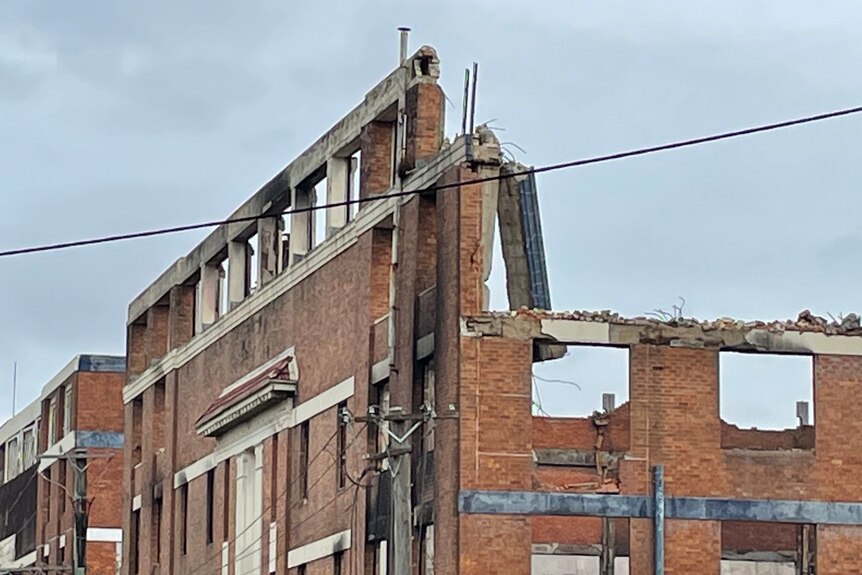 A large brick building being demolished.