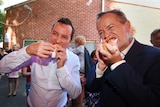 Mark McGowan and Bill Shorten bite into some sausage sandwiches at a polling booth in Perth
