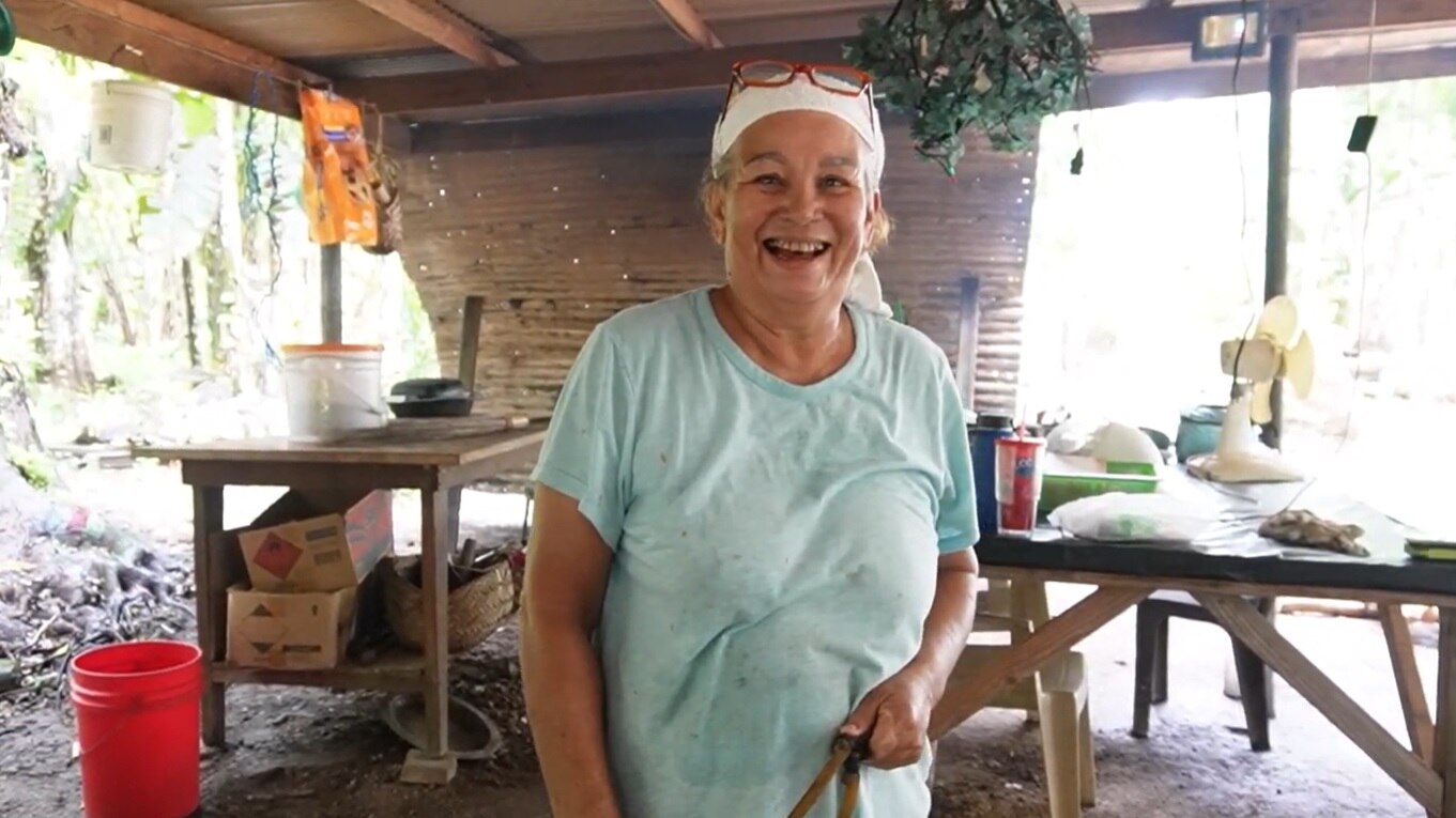 A woman wearing a bandana stands in her open-style house in Angaur