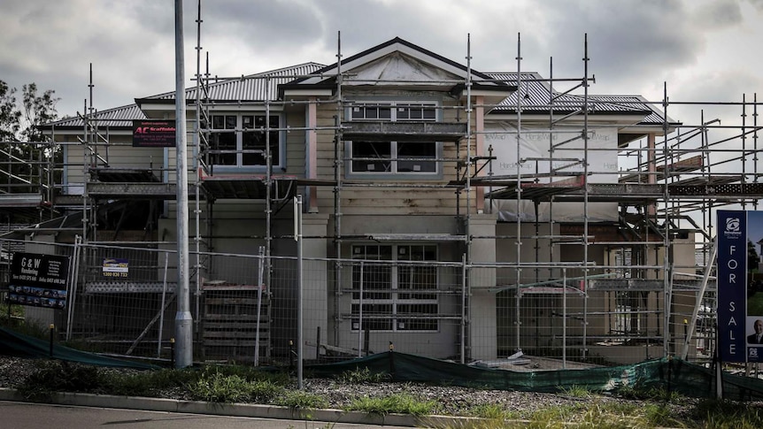 a barely constructed house with a for sale sign next to it