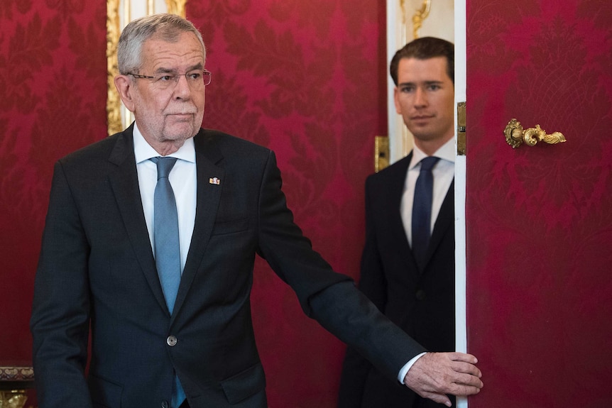 Austrian President Alexander Van der Bellen looks like he's closing a door on Kurz in a red wallpapered room.