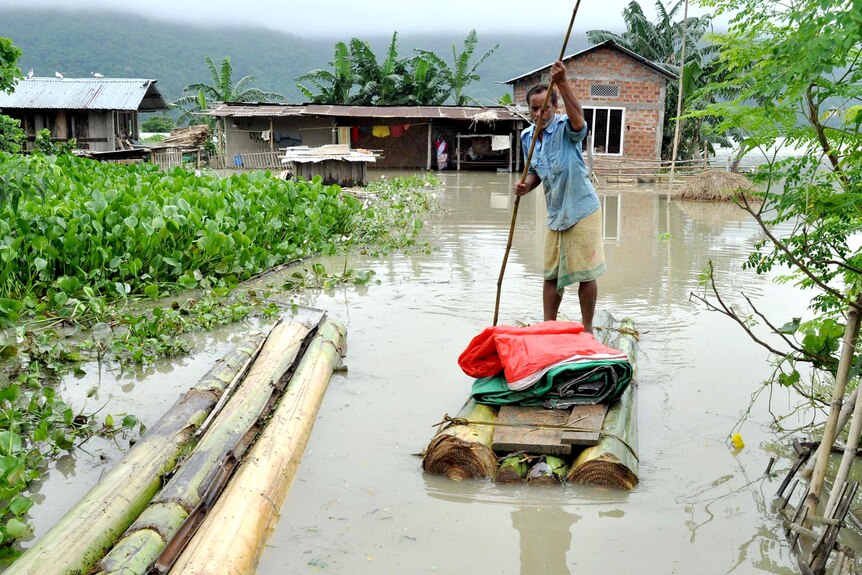 A man paddles a banana raft through floodwaters in the village of Mayong.