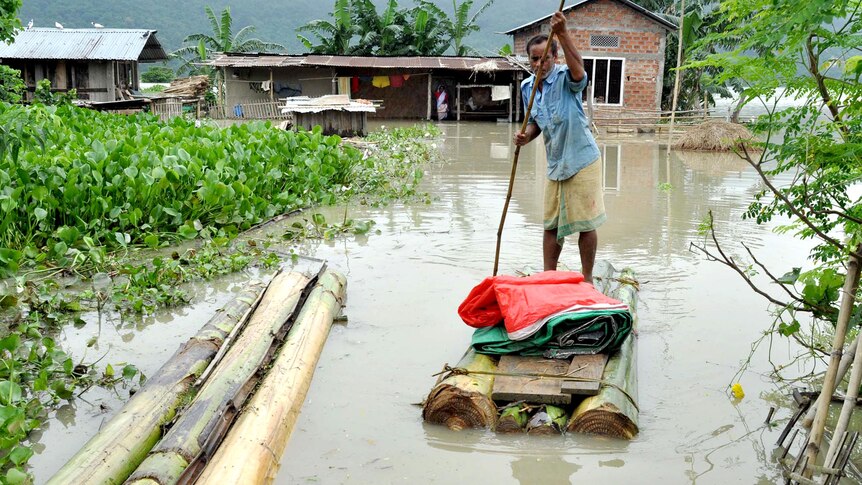 A man paddles a banana raft through floodwaters in the village of Mayong.