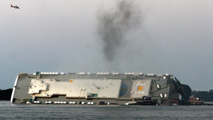 Smoke rises from a cargo ship that capsized.
