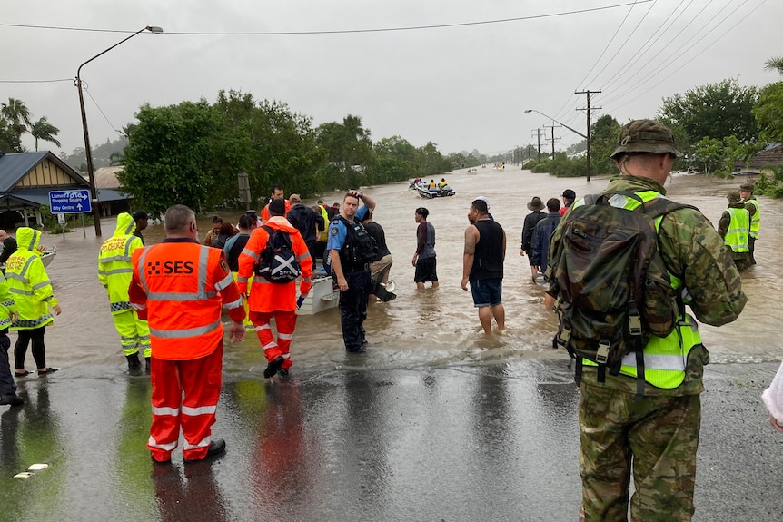 SES savanoriai ryškiai oranžinėmis striukėmis gelbėjimo potvynio vietoje.