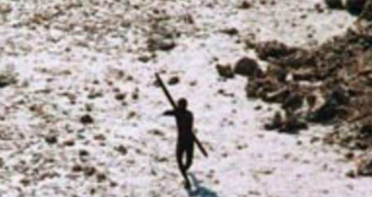 A dark figure photographed from high above pointing a bow upwards.
