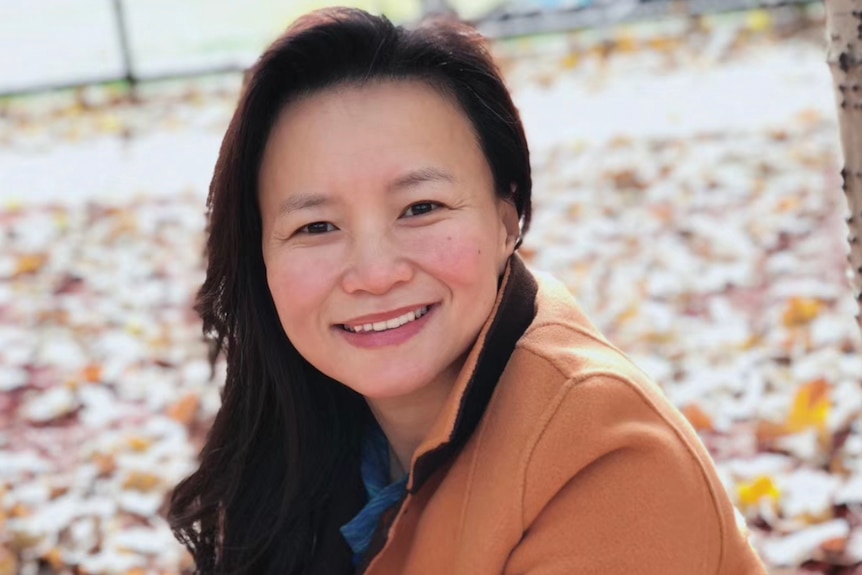 A woman wears a brown coat.